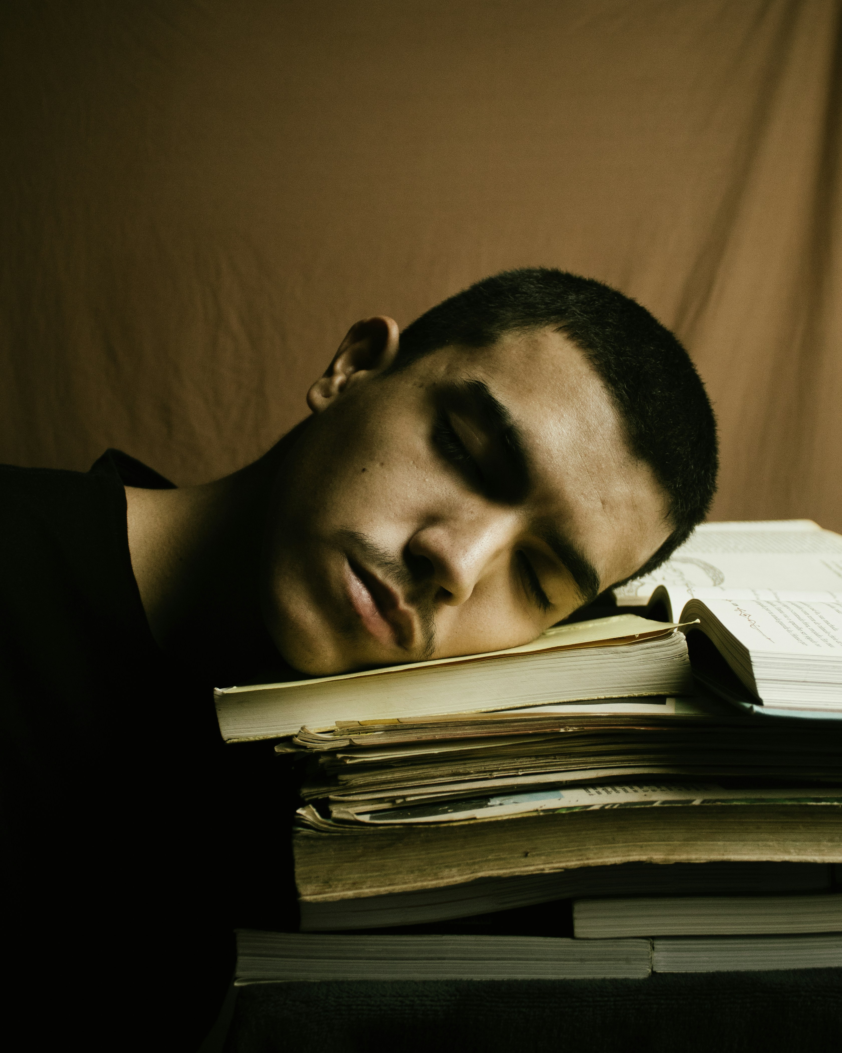 Jongen slaapt met zijn hoofd op een stapel schoolboeken